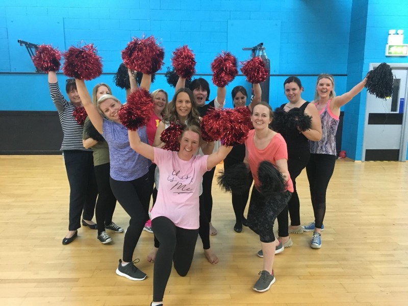 Cheerleading hen party dance class Manchester - group learning cheer moves with pom-poms in sporty outfits